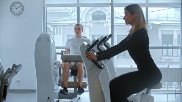 Gimnasio moderno: entrenamiento de hombres y mujeres jóvenes en un gimnasio moderno blanco — Vídeos de Stock