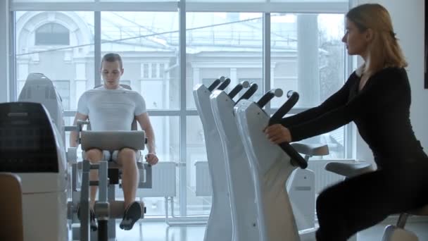 Σύγχρονο γυμναστήριο - νεαρός άνδρας και γυναίκα εκπαίδευση σε λευκό σύγχρονο γυμναστήριο με μεγάλους πανοραμικούς καθρέφτες — Αρχείο Βίντεο