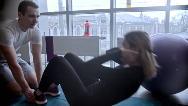 Gimnasio moderno - hombre y mujer haciendo ejercicio en el gimnasio - mujer bombeando su ABS — Vídeos de Stock