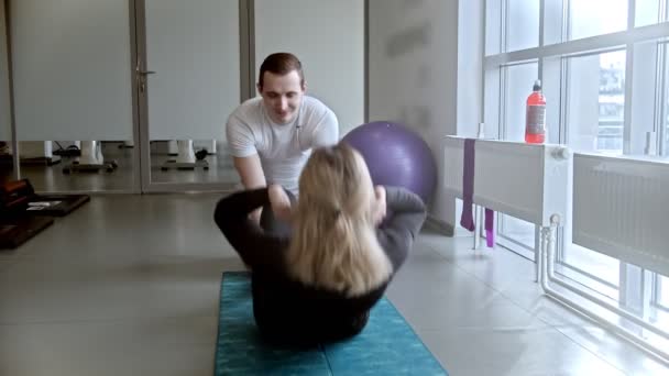 Moderne witte fitnessruimte - man en vrouw doen fitness in de sportschool - vrouw pompen haar ABS — Stockvideo