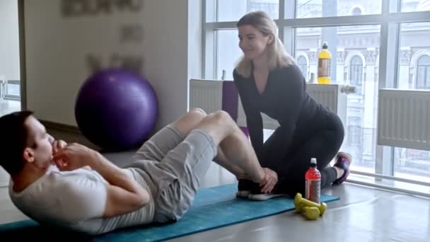 Gimnasio moderno - hombre y mujer sonrientes haciendo ejercicio en el gimnasio - hombre bombeando su ABS — Vídeos de Stock