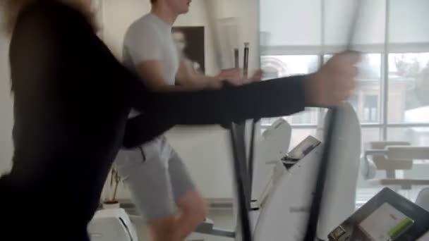 Homem e mulher esportivos em roupas esportivas treinando suas pernas em bicicleta de exercício no ginásio moderno — Vídeo de Stock