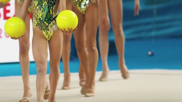 Młode kobiety nogi na turniejach gimnastyki rytmicznej - wychodzą na scenę trzymając piłki — Wideo stockowe