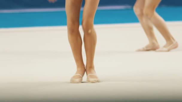 Mladé ženy nohy na rytmické gymnastiky turnaje - skákání drží míče — Stock video