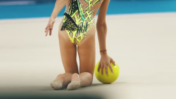 Młode kobiety nogi na turniejach gimnastycznych - dziewczyna w sportowym stroju kąpielowym wypycha piłkę na scenę — Wideo stockowe
