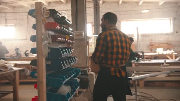 Industria de la carpintería - hombre caminando al stand con diferentes tornillos — Vídeos de Stock