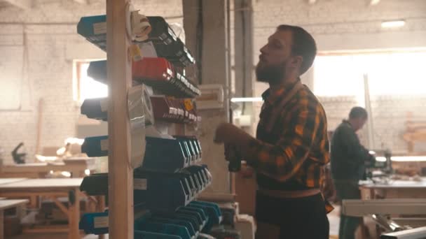 Snickeriindustrin - skäggigt mansarbetare som går till montern med olika skruvar — Stockvideo