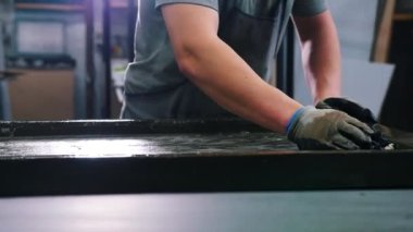 Beton atölyesi. Yüzeyi özel bir çözeltiyle silen bir adam.