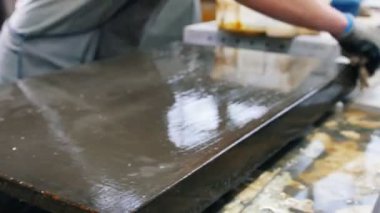 Beton atölyesi. Adam bez parçasıyla gri beton levhaları siliyor.