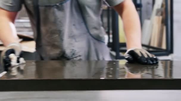 コンクリートのワークショップ-グレーのTシャツの男は、ラグでコンクリートスラブを拭くことです — ストック動画