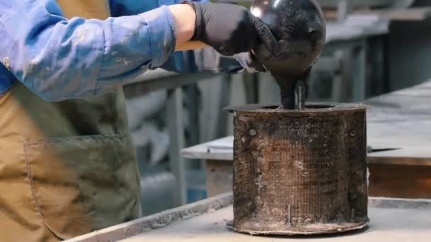 Oficina de concreto - o mestre em traje azul derramando concreto em uma forma especial redonda — Vídeo de Stock