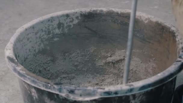 Beton műhely - egy hatalmas csavar keveri a száraz beton keveréket egy vödörben — Stock videók