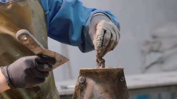 Betong verkstad - en man med en spatel smetning resterna av betong i form — Stockvideo