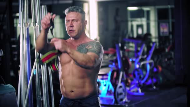 Een volwassen man bodybuilder die speciaal verband om zijn polsen doet — Stockvideo