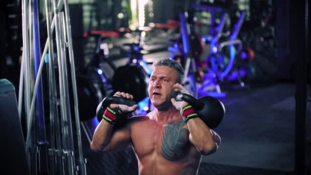 Um homem adulto fisiculturista realizando levantamento pesado kettlebells — Vídeo de Stock
