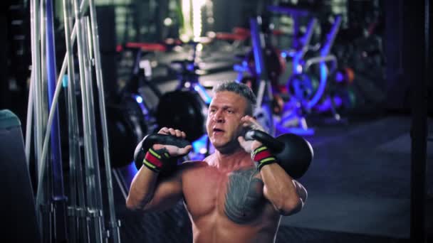 An adult man bodybuilder performing lifting heavy kettlebells — Stock Video