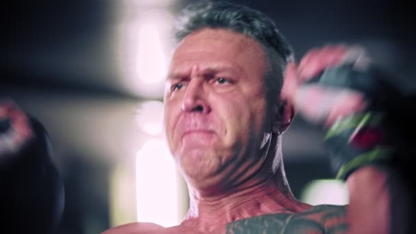 Hombre duro con el pelo gris poniendo esfuerzo en el levantamiento de pesas — Vídeos de Stock