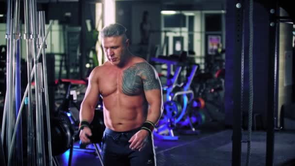 Un bodybuilder homme adulte couvrant ses mains de talc et commence à jeter un poids vers le haut et l'attrape — Video