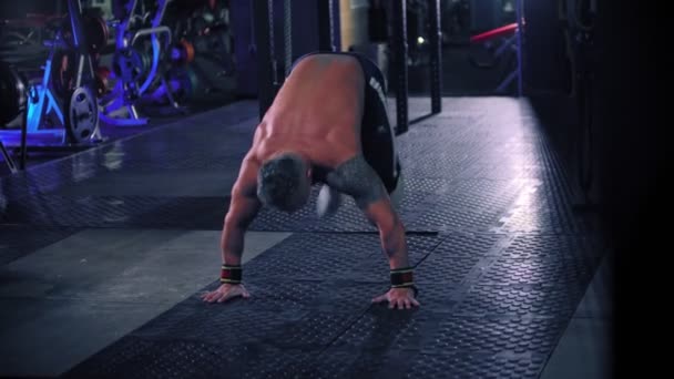 Een volwassen stoere man bodybuilder met tatoeage op de schouder doet de burpee oefening — Stockvideo