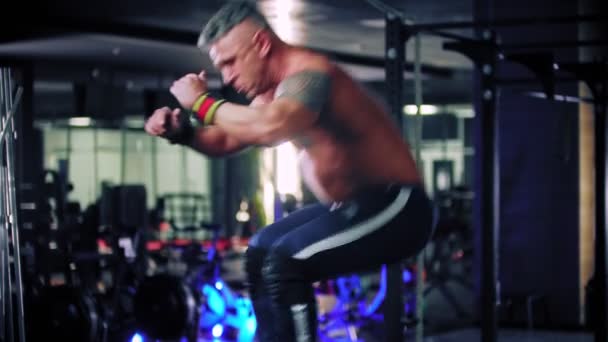 Um adulto homem duro fisiculturista pulando dentro e fora do cubo no ginásio — Vídeo de Stock