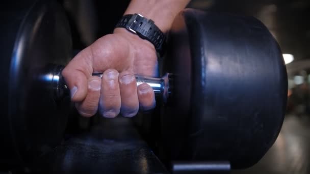 Una mano de hombre toma pesadas pesas pesadas del estrado y las devuelve — Vídeo de stock