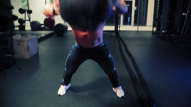 Um fisiculturista homem correndo e levanta uma bola pesada e deixa cair de volta no chão — Vídeo de Stock