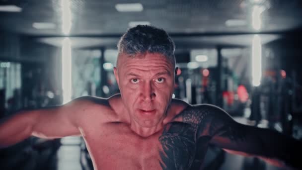 Жорсткий чоловік з сивим волоссям тренує руки в спортзалі — стокове відео
