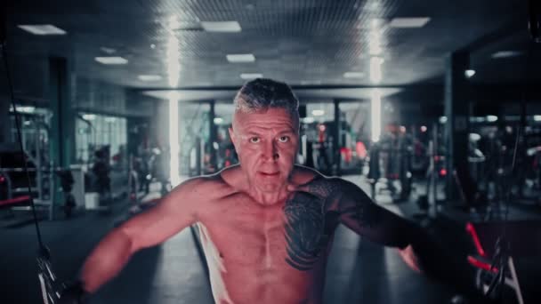 Жорсткий чоловік з сивим волоссям тренує руки в тренажерному залі за допомогою тренувального симулятора рук — стокове відео