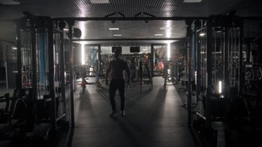 Sert adamın silueti, ellerini spor salonunda simülatör kullanarak çalıştırıyor.