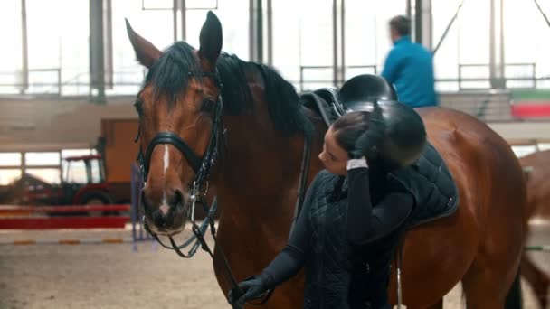 Joven jinete de pie cerca del caballo y se quita el casco — Vídeos de Stock