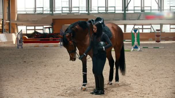 Hippodrom - junge und schöne Frau, die neben ihrem Pferd steht und einen Helm in der Hand hält — Stockvideo