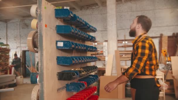 Trabalhador barbudo escolhendo parafusos do estande na oficina de carpintaria — Vídeo de Stock