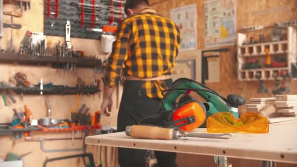 Trabalhador de homem barbudo em camisa amarela escolher instrumentos na oficina — Vídeo de Stock