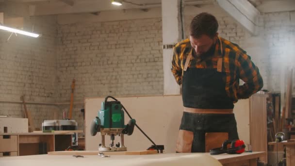 Tesařský průmysl - pracovník si nasadí zástěru a začne pracovat s bruskou — Stock video