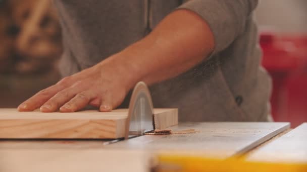 Industria de carpintería - trabajador del hombre que corta una pequeña pieza de madera usando una gran sierra circular — Vídeos de Stock