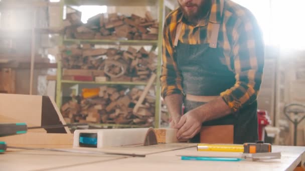 Hombre trabajador cortando un trozo de madera con una sierra circular en un taller — Vídeos de Stock