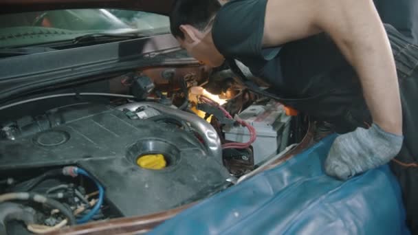 Taller de reparación de automóviles - trabajador joven examina el coche bajo el capó — Vídeo de stock