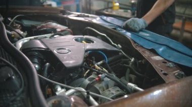Araba tamirhanesi. Motor kaputun altında çalışıyor.