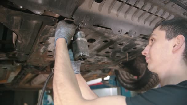 Taller de reparación de automóviles - hombre trabajador desconectar la cubierta debajo del coche — Vídeo de stock