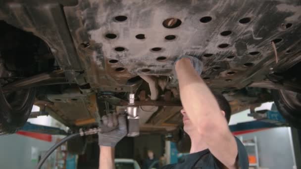 Automatikus javítóműhely - férfi munkavállaló húzza le a fedelet az autó alatt a további munka — Stock videók
