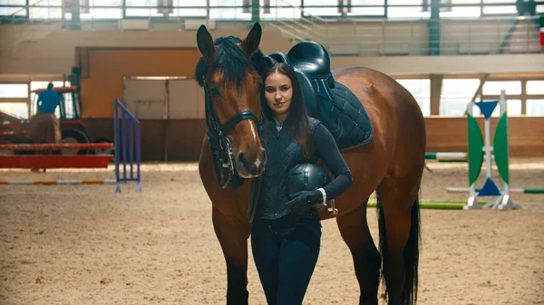 Hippodrome - young smiling woman rider standing with her horse and looking at the camera — Stock Photo, Image