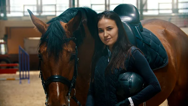 Ипподром - молодая женщина-всадник, стоящая с лошадью и смотрящая в камеру — стоковое фото