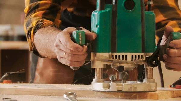 Столярная промышленность - Человек-рабочий вырезает узоры из деревянной доски — стоковое фото