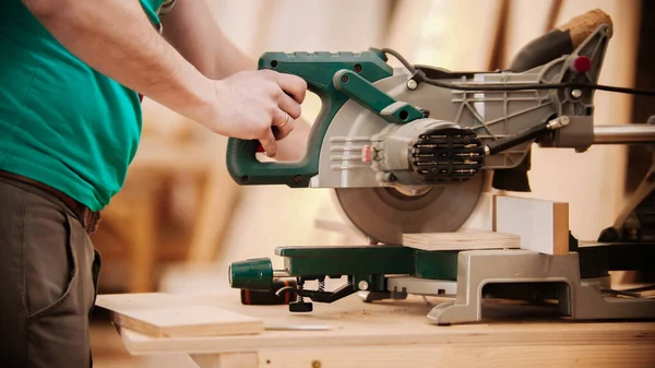 Trabajos de carpintería - hombre cortando la pieza de madera usando una gran sierra circular — Foto de Stock