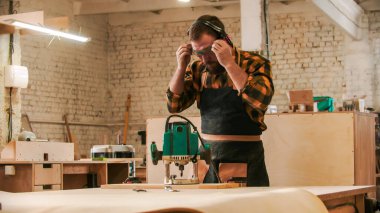 Marangozluk endüstrisi - sakallı erkek işçi koruyucu gözlük ve kulaklık takıyor