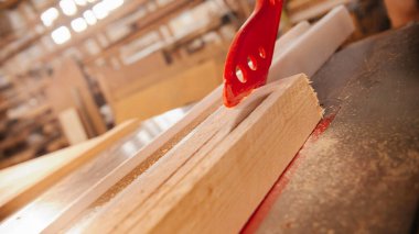 Dairesel testerenin altındaki tahta tahtayı plastik bir sopayla itiyorum.