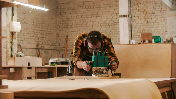 大工仕事-保護眼鏡やヘッドフォンの作業者は、ワークショップで木製のアイテムを研削 — ストック写真
