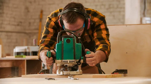 木工業界-木製の板からパターンをカット保護メガネやヘッドフォンの男の労働者 — ストック写真