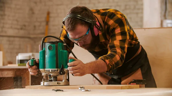 Столярная промышленность - человек вырезает узоры из деревянной доски — стоковое фото
