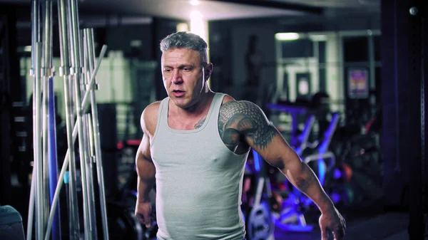 An adult man in grey shirt bodybuilder standing in the gym — Stock Photo, Image